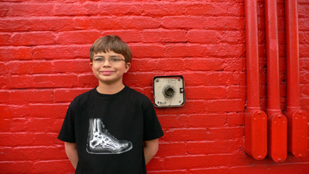 Alex in front of a red wall at Little Five Points.