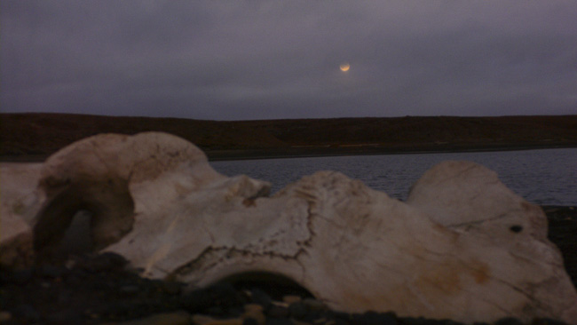 Shot of the full moon peeking out from behind the clouds as the sun was setting behind me at the Wiley Post Monument ten miles west of Barrow.  (2007)